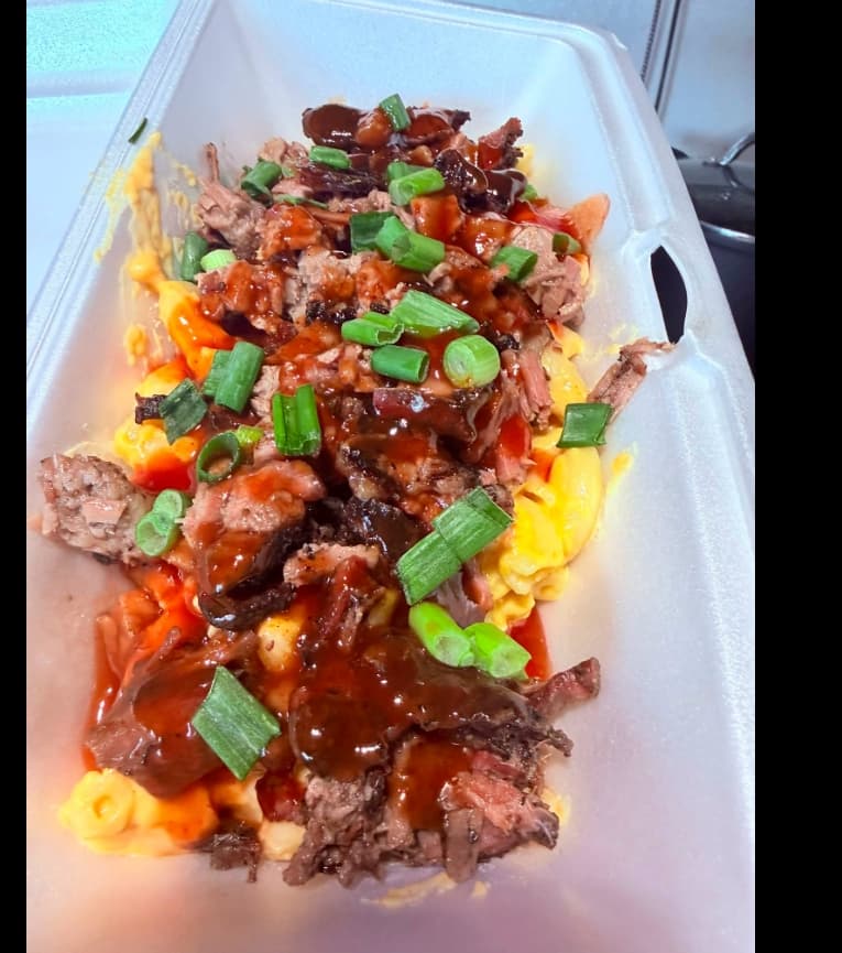 Baked mac and cheese loaded with chopped brisket, green onion, and BBQ sauce