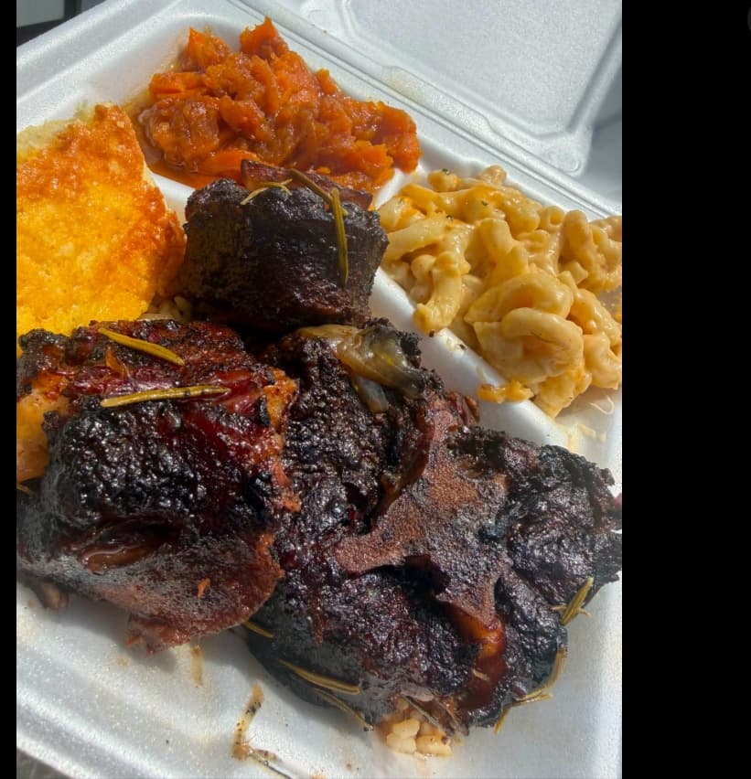 Plate of smoked meat with candied yams, mac and cheese, and cornbread