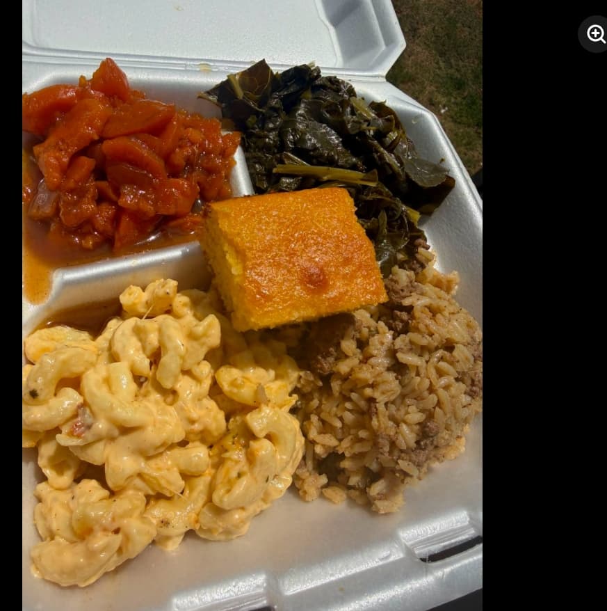 Plate of collard greens, candied yams, mac and cheese, dirty rice, and cornbread